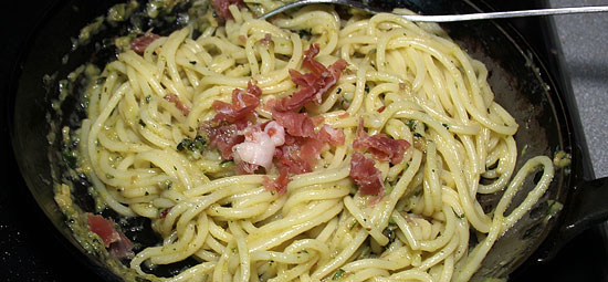 Spaghettini mit Sauce und Parmaschinken vermischen