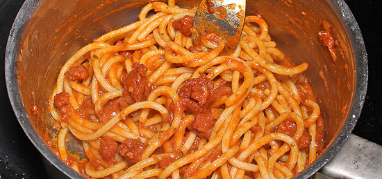 Spaghetti mit dem Sugo vermischen